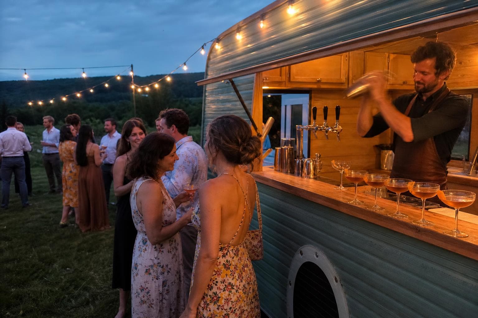 Un barman prépare des cocktails dans une roulotte-bar, à un mariage en soirée